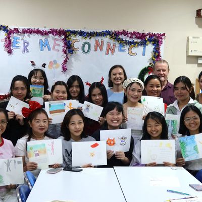 PND volunteers and students are displaying their drawings and smiling for the camera.