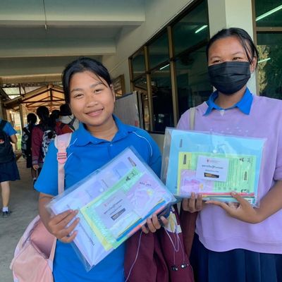 The students are happily smiling showing self-learning kits for the camera.