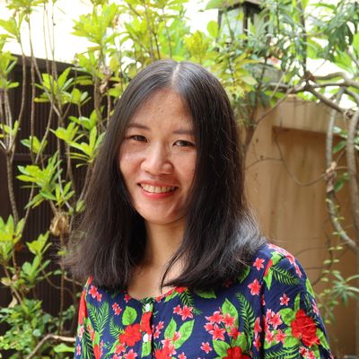 Woman with floral shirt smiling in a garden